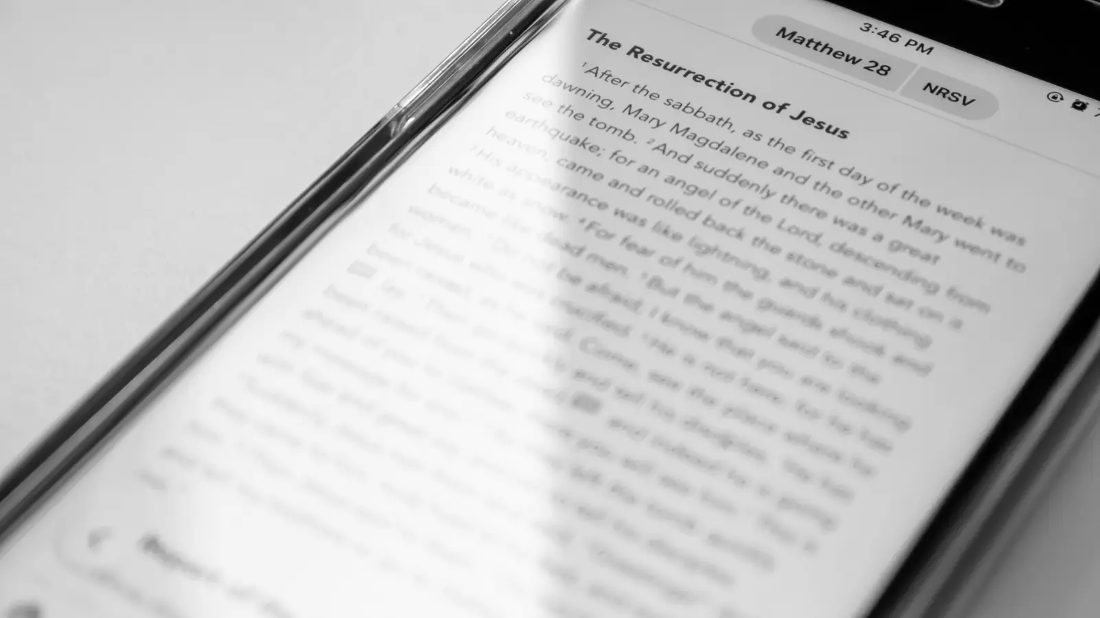 Black and white close-up of a phone screen showing Matthew 28 in a Bible reading app.